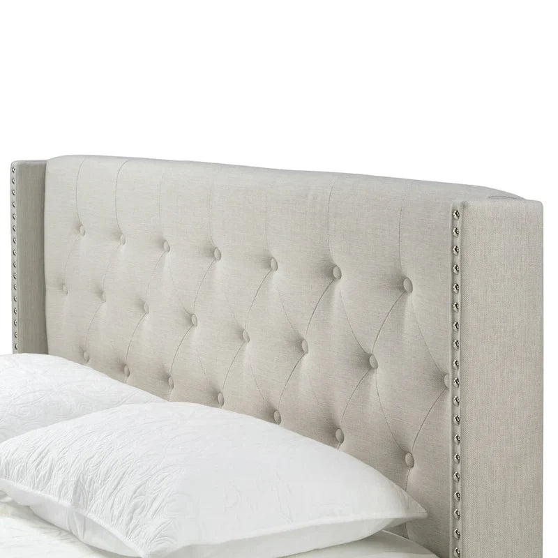 Lit en tissu beige avec capitonnage et ailes cloutées
