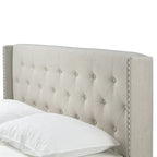 Lit en tissu beige avec capitonnage et ailes cloutées